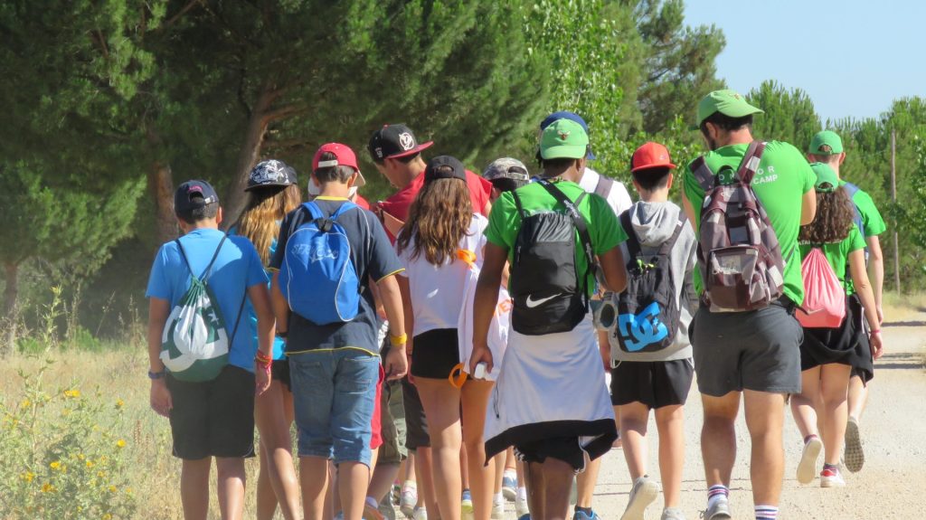 Un grupo de personas caminando juntas por un camino de tierra rodeado de vegetación.